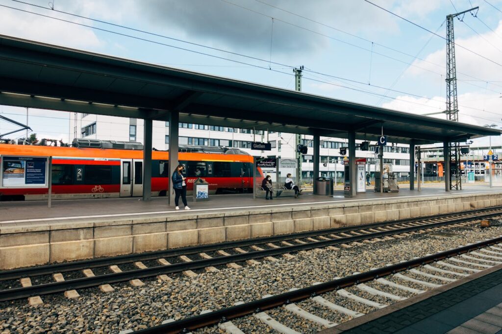 A view of a train station platform with an orange train arriving.