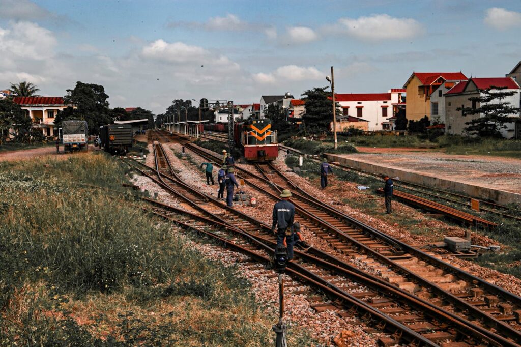 A train traveling along the tracks, surrounded by greenery and a clear blue sky.