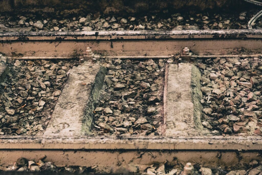 Close-up of a train track surrounded by gravel and rocks, highlighting the texture and arrangement of the materials.