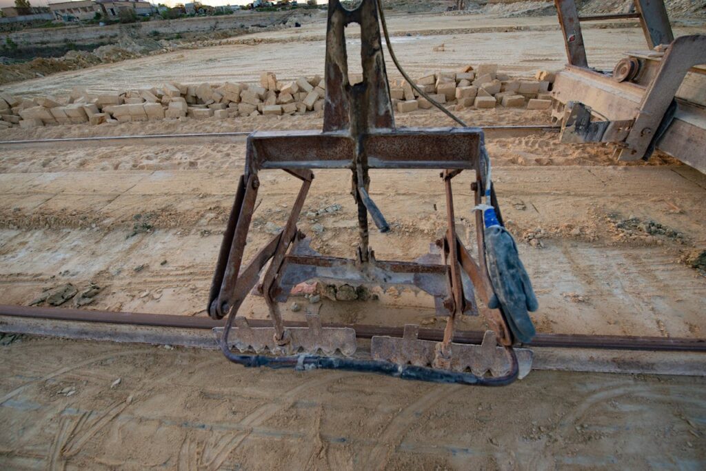 A large piece of machinery rests on a dirt field, surrounded by an open landscape under a clear sky.